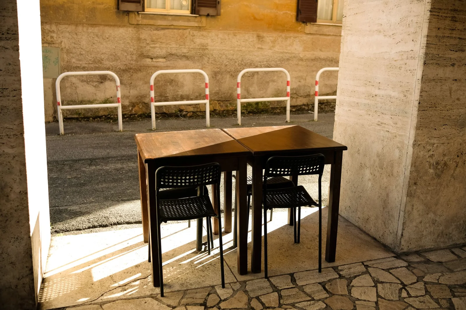 Terrasse bordelaise en lumière de fin d'après-midi, tables alignées le long d'une façade en pierre