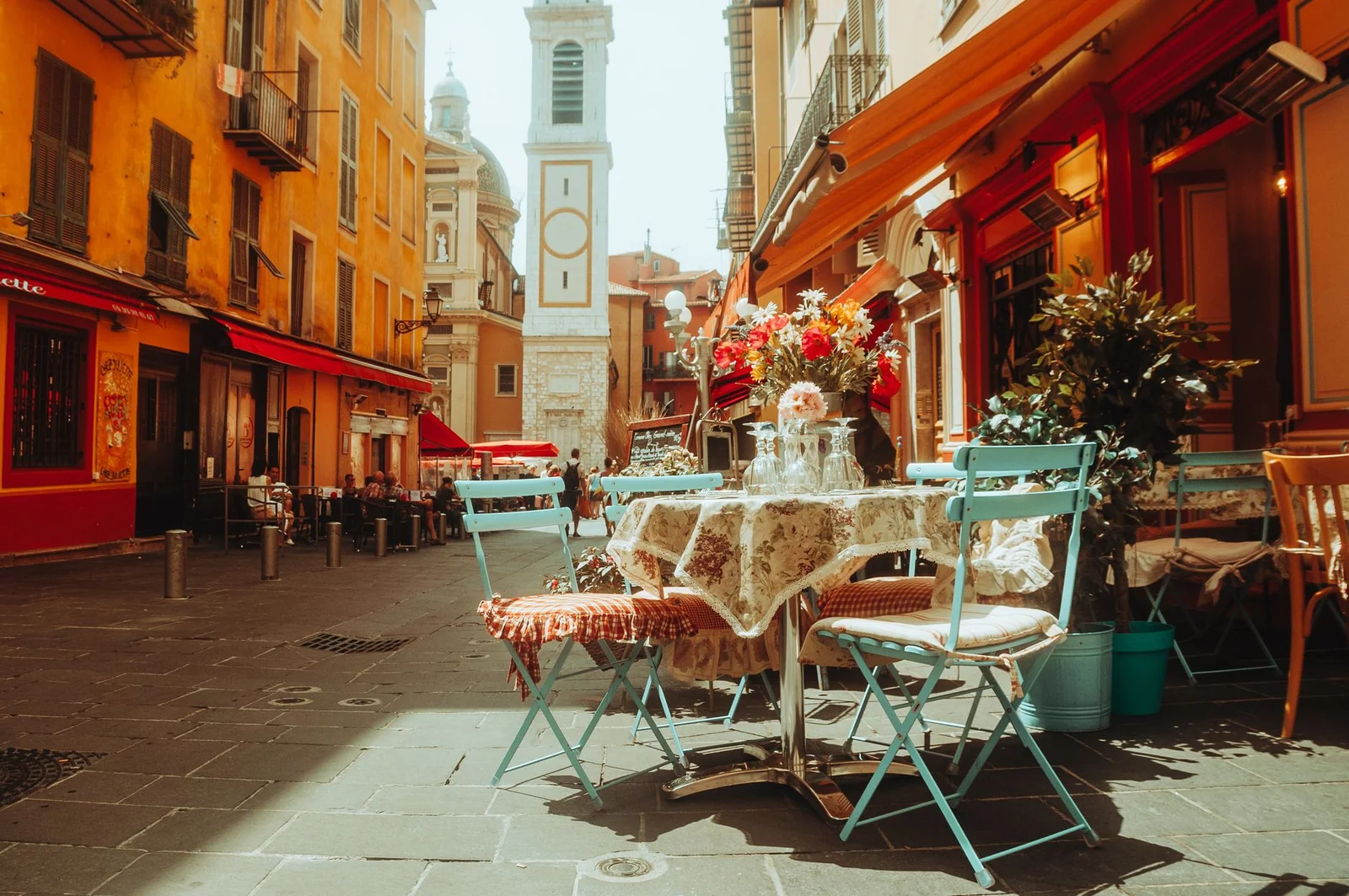 Terrasse de café bordelais en fin d'après-midi, tables en lumière dorée